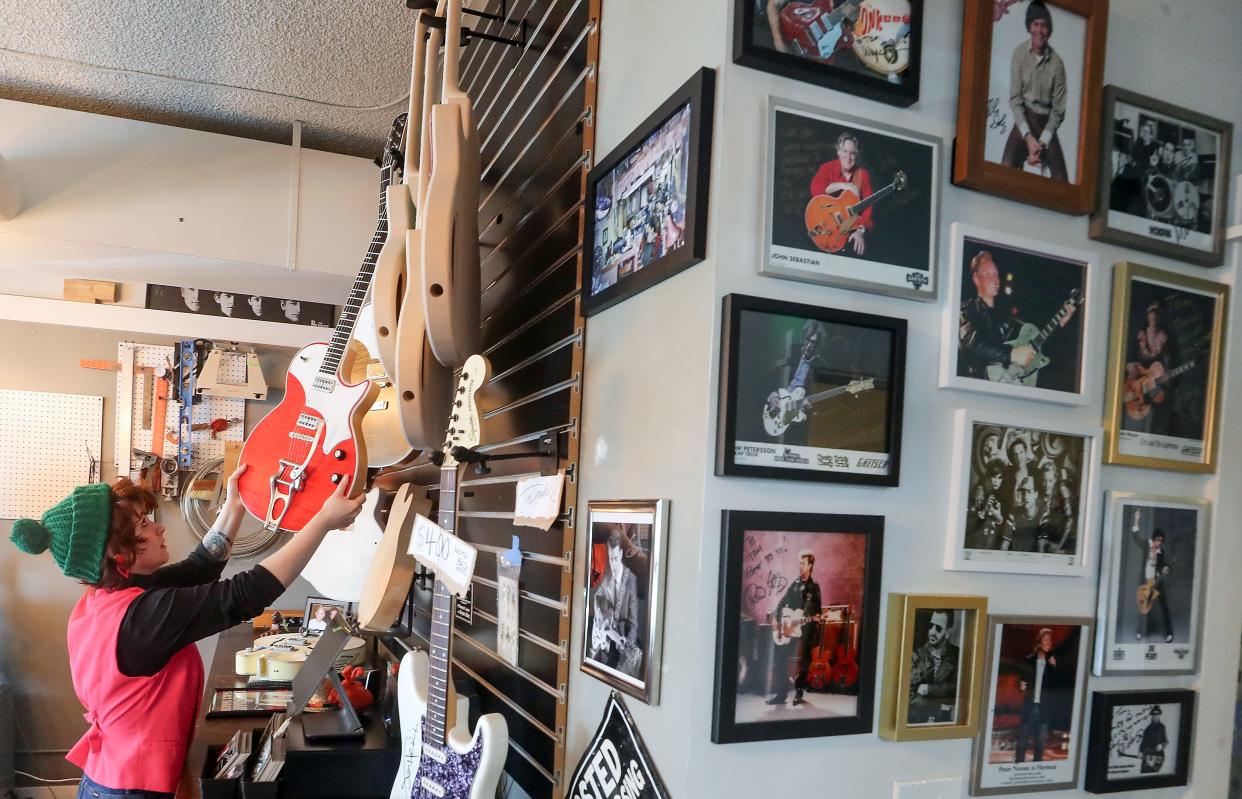 Cheyenne Sibitzky hangs a custom guitar back up on the wall at TV Jones in Poulsbo on Thursday, April 11, 2024.