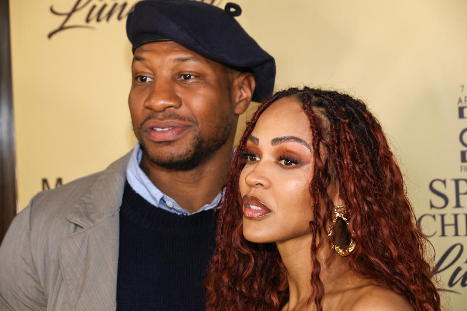 Jonathan Majors and Meagan Good attending a celebrity event. Jonathan is wearing a beret and a casual jacket while Meagan has curly hair and wears a stylish top