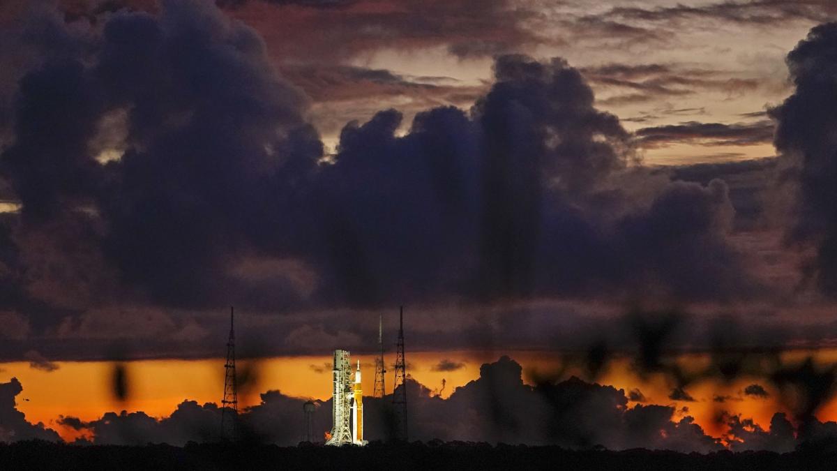 Spectators watch a sunrise from the Max Brewer Bridge while waiting to view  the launch on Pad 39B for the Artemis I mission to orbit the moon at the  Kennedy Space Center