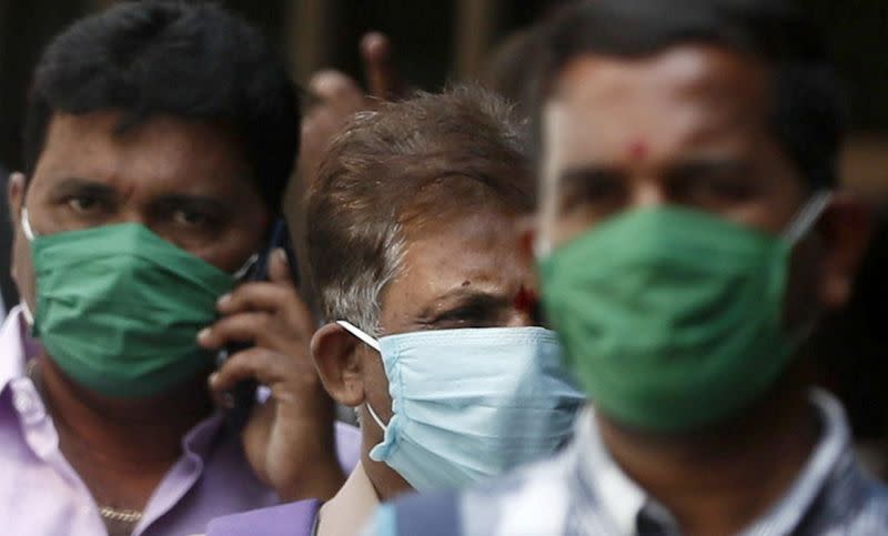 Men wearing protective masks walk inside the premises of a hospital where a special ward has been set up for the coronavirus disease in Mumbai
