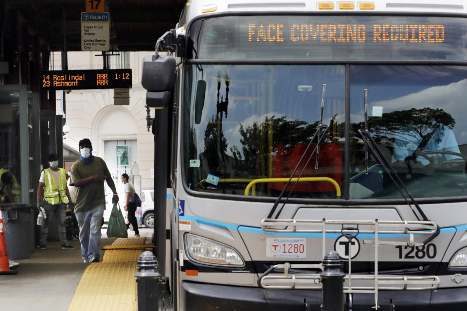 FILE- In this June 24, 2020, file photo, a man, wearing a protective face mask, rushes to catch his bus at Dudley Station in Nubian Square in Boston. Face coverings are required on all buses, subways, trains and trolleys in Boston due to the COVID-19 virus outbreak. The CDC is strongly recommending that passengers on planes, trains and buses wear masks, but it's still stopping short of requiring face coverings to prevent spreading COVID-19. The CDC says masks should be worn by all passengers and workers on planes, ferries, trains, subways, buses, taxis and ride-sharing vehicles. (AP Photo/Charles Krupa, File)