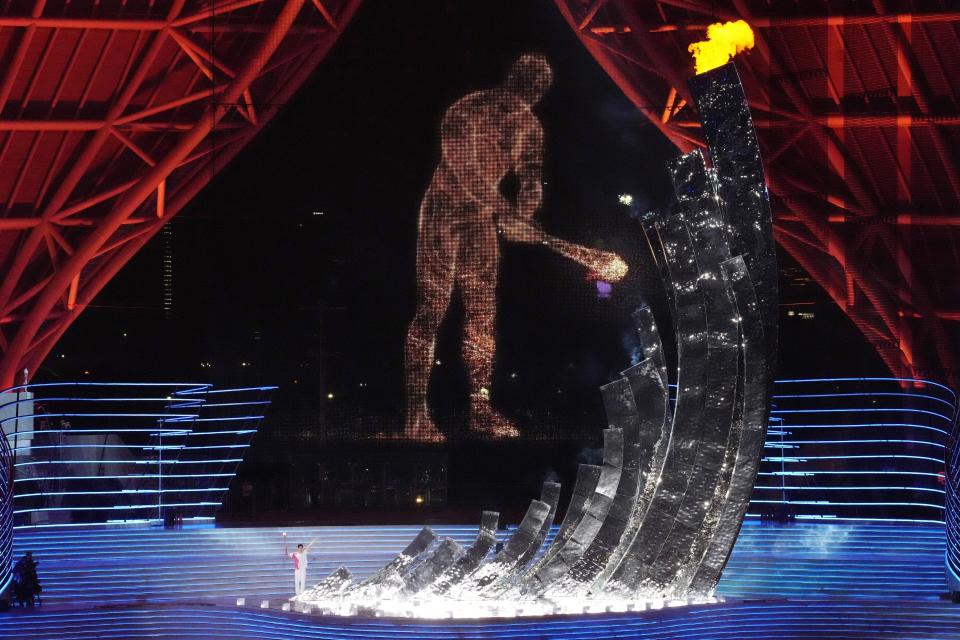 Chinese swimmer Wang Shun holds the torch to light the cauldron with a digital torchbearer inn background during the opening ceremony of the 19th Asian Games in Hangzhou, China, Saturday, Sept. 23, 2023. (AP Photo/Eugene Hoshiko)