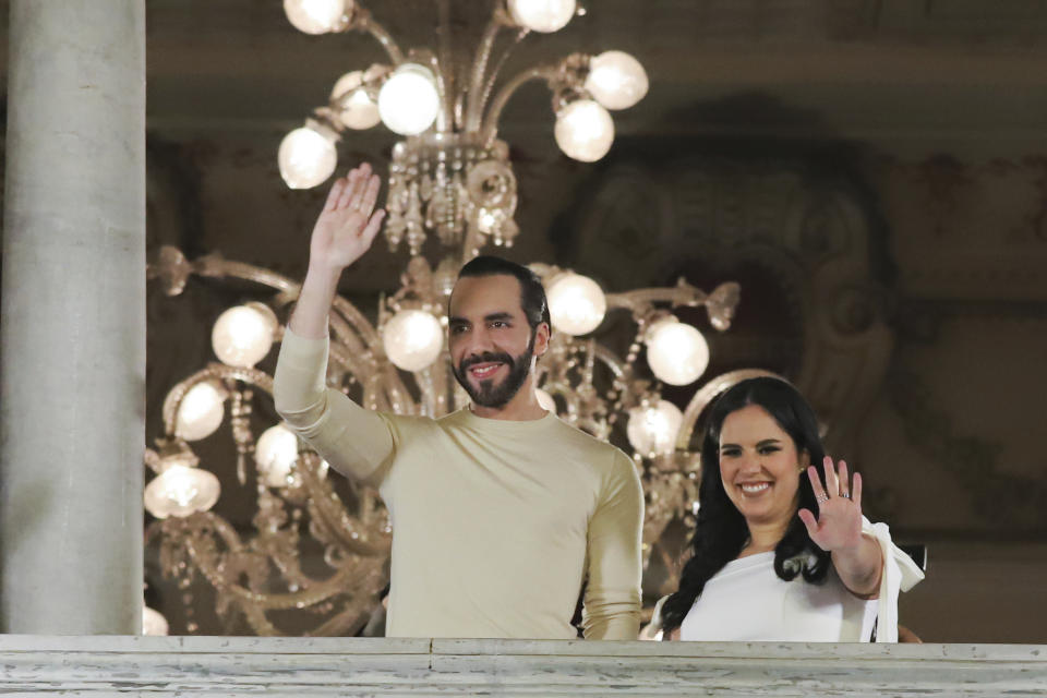 El Salvador President Nayib Bukele, left, accompanied by his wife Gabriela Rodriguez, wave to supporters from the balcony of the presidential palace in San Salvador, El Salvador, after polls closed for general elections on Sunday, Feb. 4, 2024. (AP Photo/Salvador Melendez)