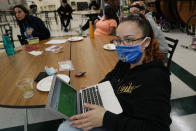 Charisma Poliandro, right, sits with several teachers as she listens during a combination trivia/current events quiz and pizza party in the cafeteria at West Brooklyn Community High School, Thursday, Oct. 29, 2020, in New York. The high school is a "transfer school," catering to a students who haven't done well elsewhere, giving them a chance to graduate and succeed. (AP Photo/Kathy Willens)