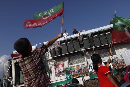 Imran Khan, chairman of the Pakistan Tehreek-e-Insaf (PTI) political party, addresses supporters as children wave PTI's flag, in front of the Parliament building during the Revolution March in Islamabad August 29, 2014. REUTERS/Akhtar Soomro