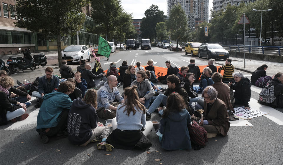 Protestors from climate activism group of Extinction Rebellion block a busy intersection near the temporary home of the Dutch parliament in The Hague, Netherlands, Monday, Oct. 11, 2021. The group says it plans a series of demonstrations in the city throughout the week ahead of a major United Nations climate conference that opens Oct. 31, in Glasgow. (AP Photo/Patrick Post)