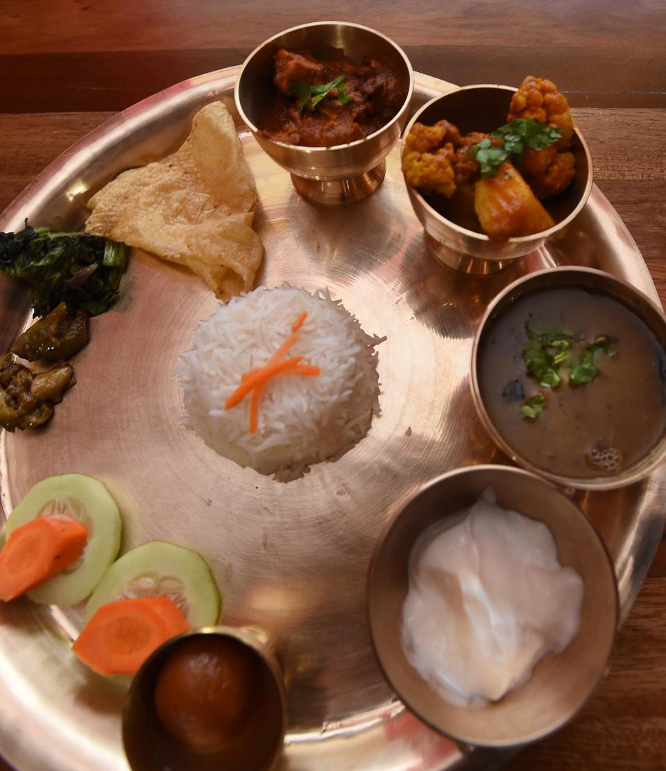 A popular dish at Annapurna Kitchen is the chicken thali, served on a platter with rice, cucumber slices, cauliflower and a dessert called "gulab jamun."