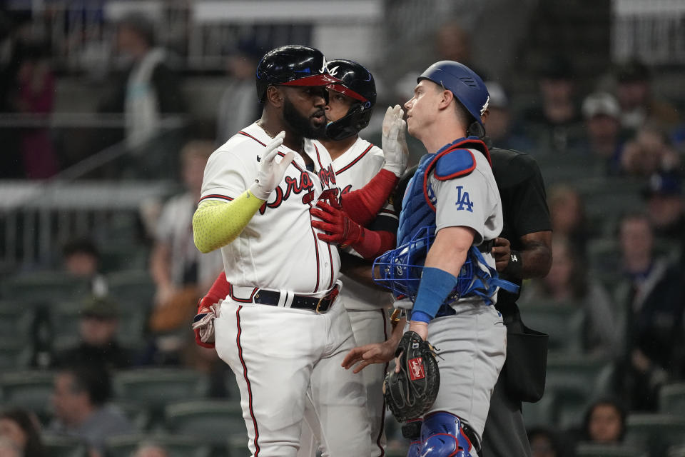 An umpire, back right, steps between Atlanta Braves designated hitter Marcell Ozuna, left, and Los Angeles Dodgers catcher Will Smith, right, as they exchange words in the fourth inning of a baseball game, Monday, May 22, 2023, in Atlanta. (AP Photo/John Bazemore)