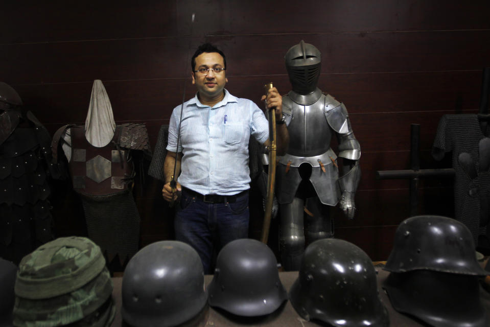 In this, June 2, 2012 photograph, Delhi businessman Ashok Rai, weapons and attire maker of war movies set from the 10th century to World War II, poses with helmets from different periods and a body armor at his workshop in Sahibabad, India. From Hollywood war movies to Japanese Samurai films to battle re-enactments across Europe, Rai is one of the world's go-to men for historic weapons and battle attire. (AP Photo/Saurabh Das)
