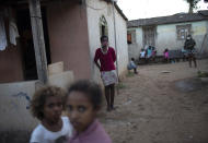 A woman stands in front of her home as donated food and kits of cleaning products and protective face masks are distributed at the Maria Joaquina "Quilombo" in Cabo Frio, Brazil, on the outskirts of Rio de Janeiro, Sunday, July 12, 2020. "Quilombo" residents are accustomed to communal life, but the pandemic has broken traditional bonds by forcing people to wear masks and quarantine in their own homes. (AP Photo/Silvia Izquierdo)