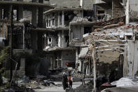 <p>Residents walk through damaged streets at the mountain resort town of Zabadani outside Damascus, May 18, 2017. A U.S. airstrike hit pro-Syrian government forces in the desert near the border with Jordan, U.S. officials and Syrian activists said, an apparent signal to President Bashar Assad to keep his forces out of a zone where U.S.-backed rebels are fighting the Islamic State group. (Photo: Hassan Ammar/AP) </p>