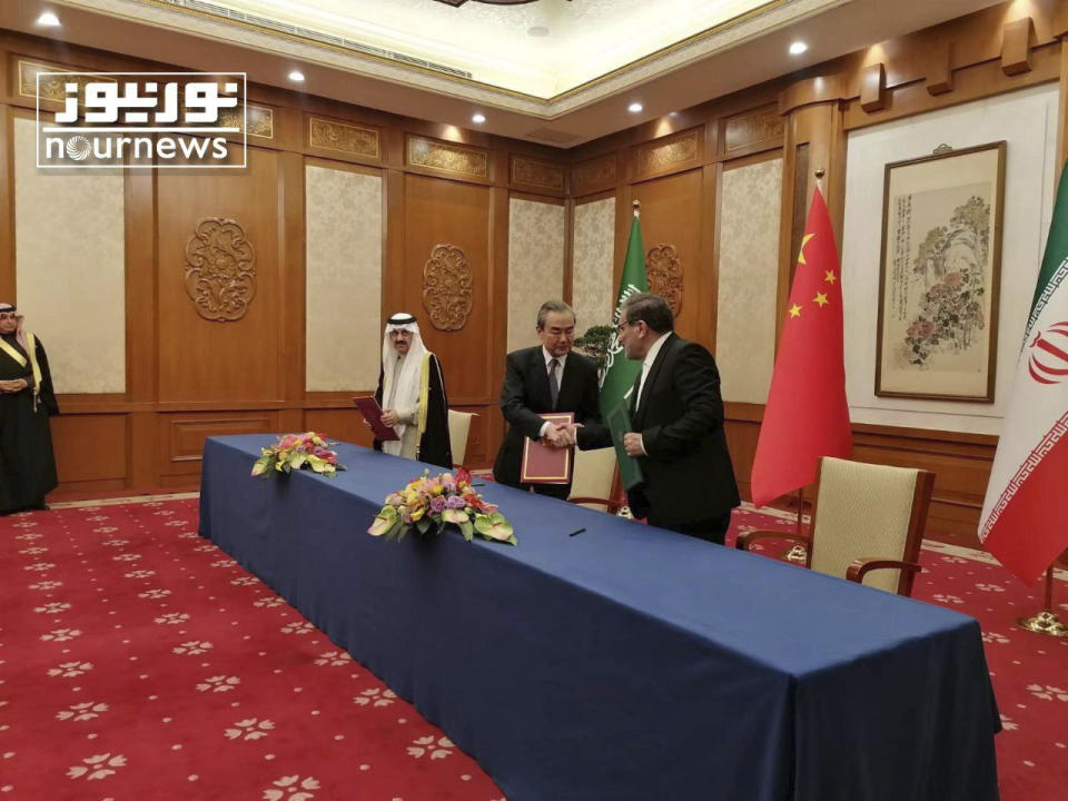 In this photo released by Nournews, Secretary of Iran's Supreme National Security Council, Ali Shamkhani, right, shakes hands with China's most senior diplomat Wang Yi, as Saudi Arabia's National Security Adviser Musaad bin Mohammed al-Aiban looks on during an agreement signing ceremony between Iran and Saudi Arabia to reestablish diplomatic relations and reopen embassies after seven years of tensions between the Mideast rivals, in Beijing, China, Friday, March 10, 2023. (Nournews via AP)