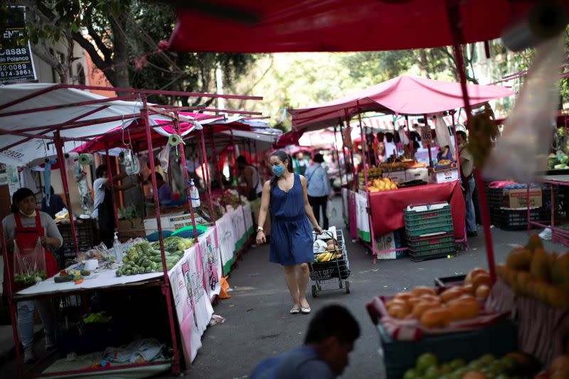 A woman is pictured between vendors at the local street market after Mexico's government declared a health emergency on Monday and issued stricter rules aimed at containing the fast-spreading coronavirus disease (COVID-19), in Mexico City