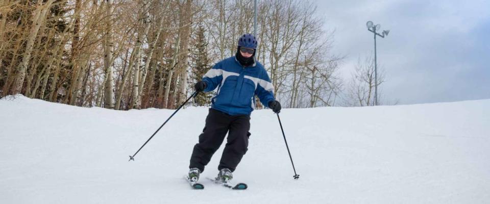 Downhill skier in his 70s skiing in Colorado, aspen trees in the background