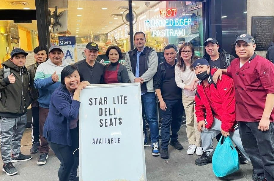 Jung Min Kim, fifth from left, and his wife, Jahee Kim, next to him, outside their deli in New York City. (Courtesy Jung Min and Jahee Kim)