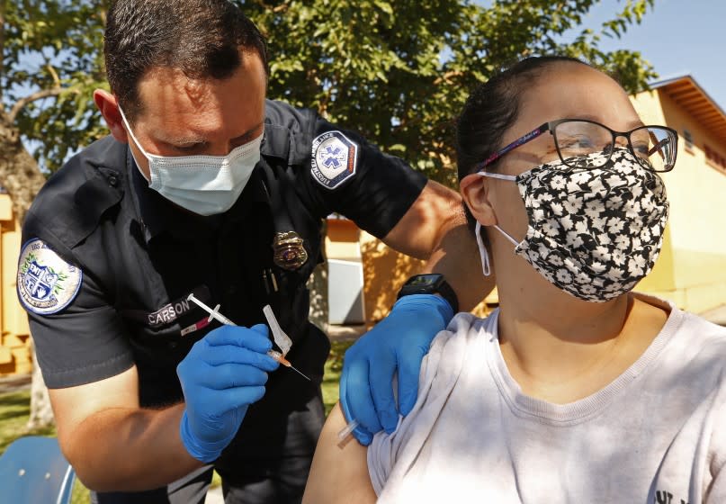 ARLETA, CA - AUGUST 02: Diana Gomez, 29 , receives her Pfizer Covid vaccine from Kyle Carson, an EMT with FirstMed Ambulance Services as the Fernandeno Tataviam Band of Mission Indians, in its participation with the Medi-Vaxx Program of the San Fernando Valley, along with El Proyecto del Barrio, Los Angeles Mission College, Mission Hospital and FirstMed Ambulance Services conducted one in a series of pop-up COVID-19 vaccination clinics at Montague Charter Academy for the Arts and Sciences in Arleta Monday morning. "After some skepticism, I'm getting the vaccine and my daughter is going back to school so I might as well get it." Gomez said. Monday's clinic administered first doses of the Pfizer and J&J vaccine and ran through noon. Montague Charter Academy for the Arts and Sciences on Monday, Aug. 2, 2021 in Arleta, CA. (Al Seib / Los Angeles Times).