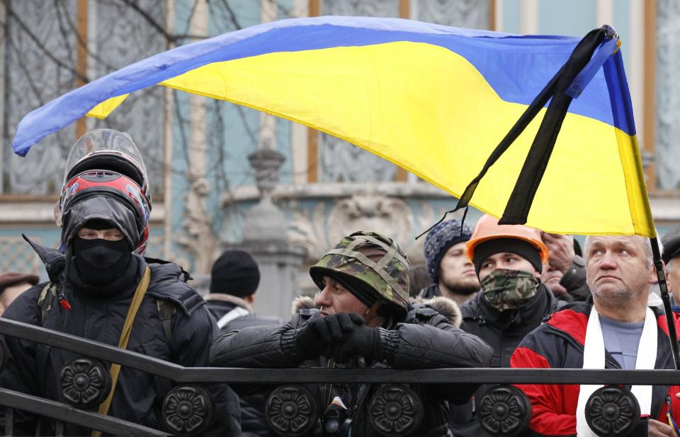 Anti-government protesters gather outside the Ukrainian Parliament building, with a black ribbon attached to a Ukrainian national flag to mark a day of mourning for the victims of clashes, in Kiev