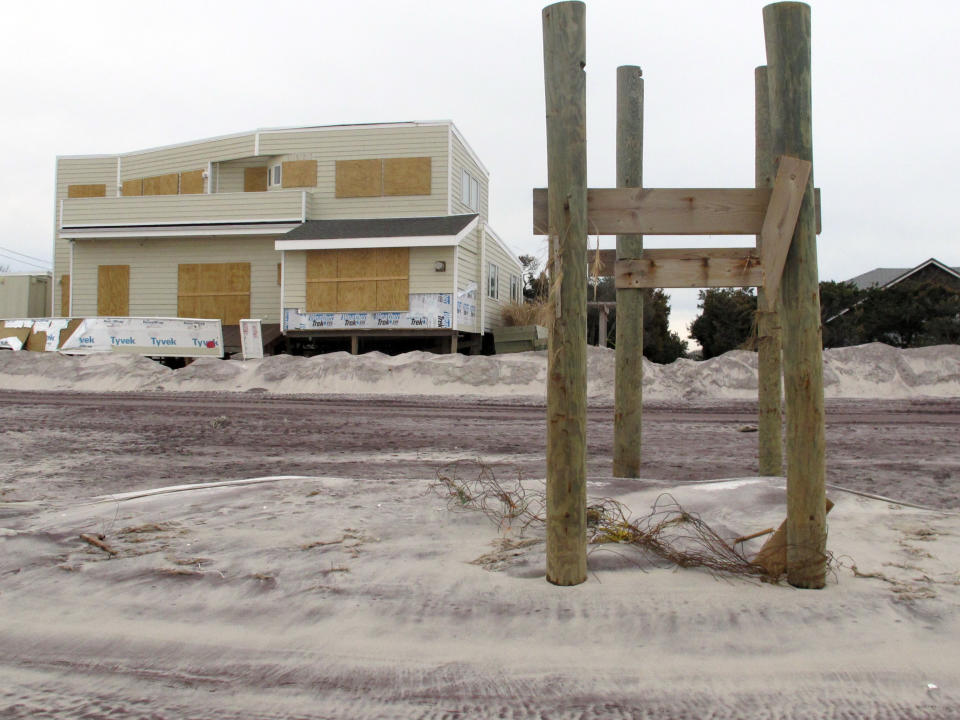 In this Friday, Nov. 16, 2012 photo, pilings that once held a walkway over dunes leading to the beach are all that remain outside a boarded up home in Ocean Beach, N.Y. The Fire Island community was damaged in Superstorm Sandy. (AP Photo/Frank Eltman)