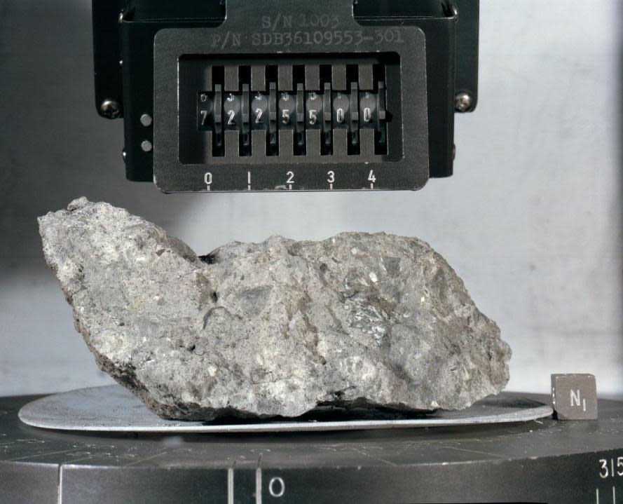 (December 1972) — A “mug shot” of Apollo 17 lunar sample no. 72255 which was brought back from the lunar surface by the final team of Apollo astronauts. The rock weighs 461.2 grams and measures 2.5 x 9 x 10.5 centimeters. The light grey breccia is sub-rounded on all faces except the top and north sides. (NASA)