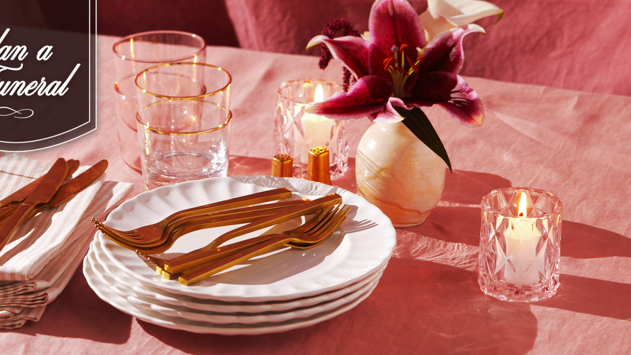 white scalloped plates with gold utensils and candles and vase on pink table cloth