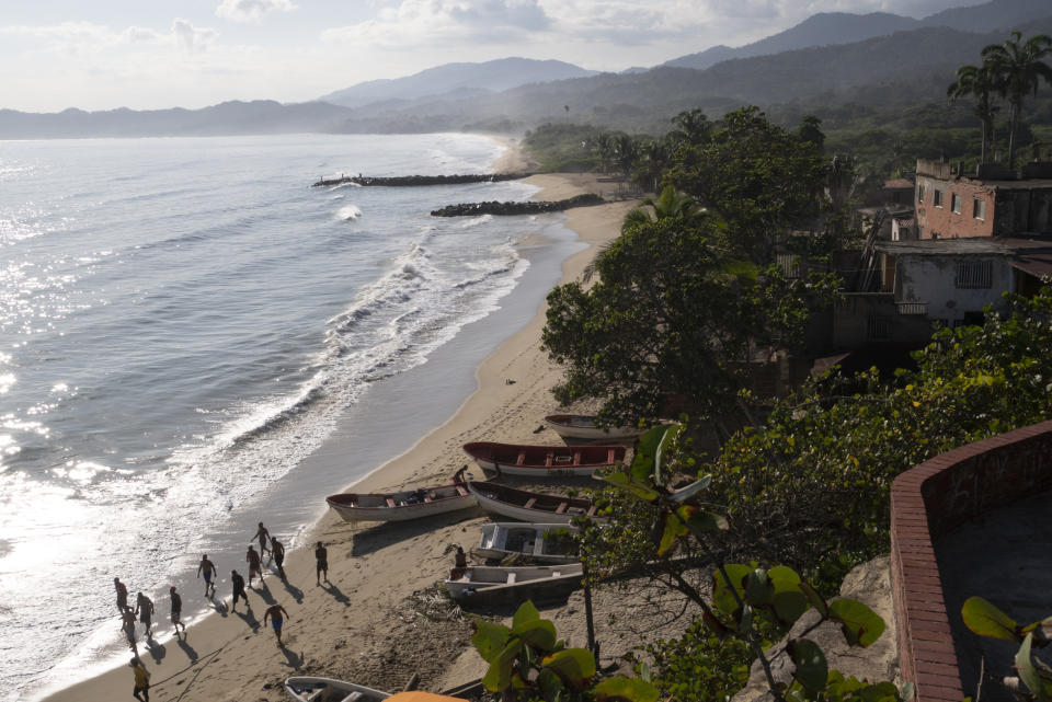 Men run to help a La Sabana fisherman pull his boat in from the sea. (Andrea Hernández Briceño for The Washington Post)