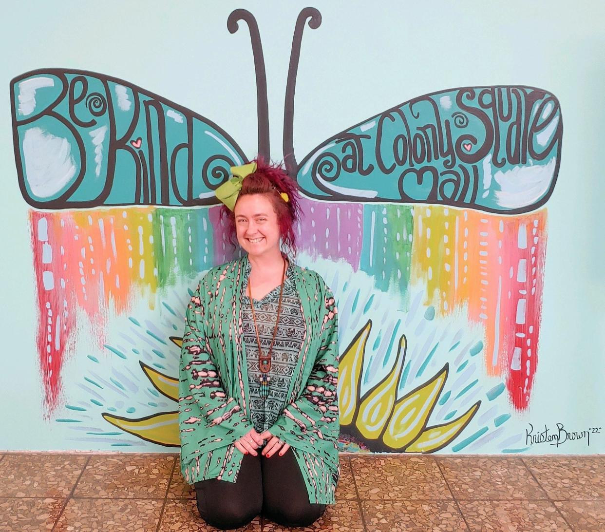 Kristen Brown, president of ArtCoz, with a one of the new murals she painted at Colony Square Mall at Café Court.