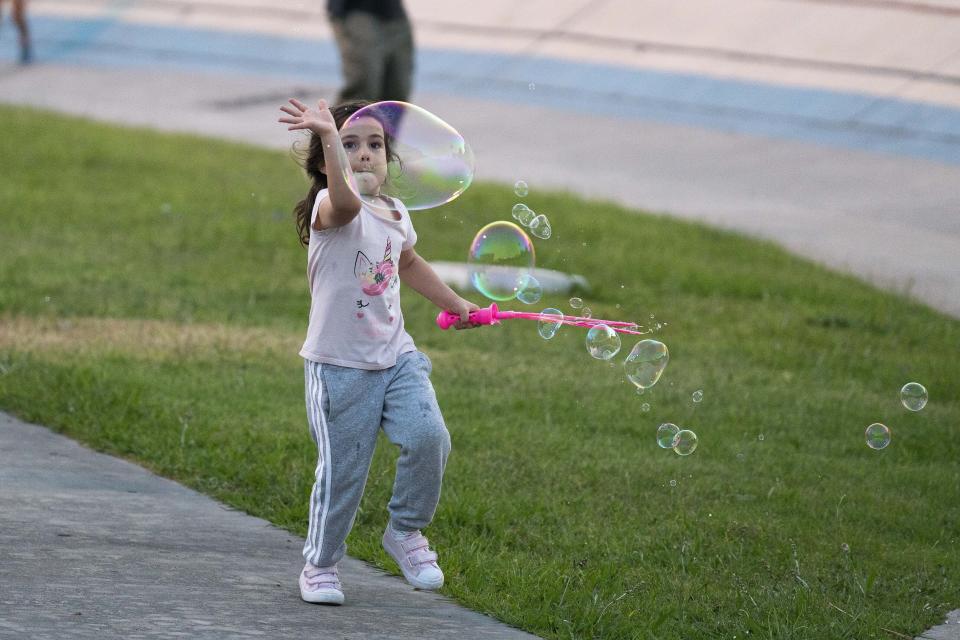 A girl chases after soap bubbles during a political event of the ruling Broad Front political party in Montevideo, Uruguay, Tuesday, Nov. 19, 2019. Uruguay will hold run-off presidential elections on Nov. 24 between Daniel Martinez and the presidencial candidate for the National Party, Luis Lacalle Pou . (AP Photo/Matilde Campodonico)