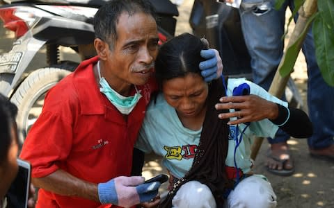 An Indonesian man tries to calm a woman shortly after an aftershock hits the area in Tanjung on Lombok island on August 9  - Credit: ADEK BERRY/AFP