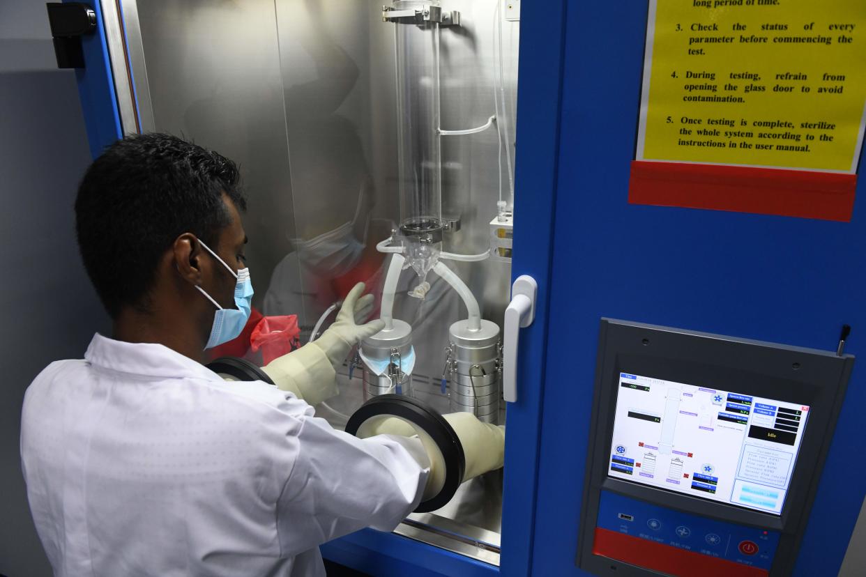 A lab technician places a face mask through a bacterial filtration efficiency tester during a media tour of a Setsco laboratory that tests surgical masks in Singapore on August 18, 2020. (Photo by ROSLAN RAHMAN / AFP) (Photo by ROSLAN RAHMAN/AFP via Getty Images)