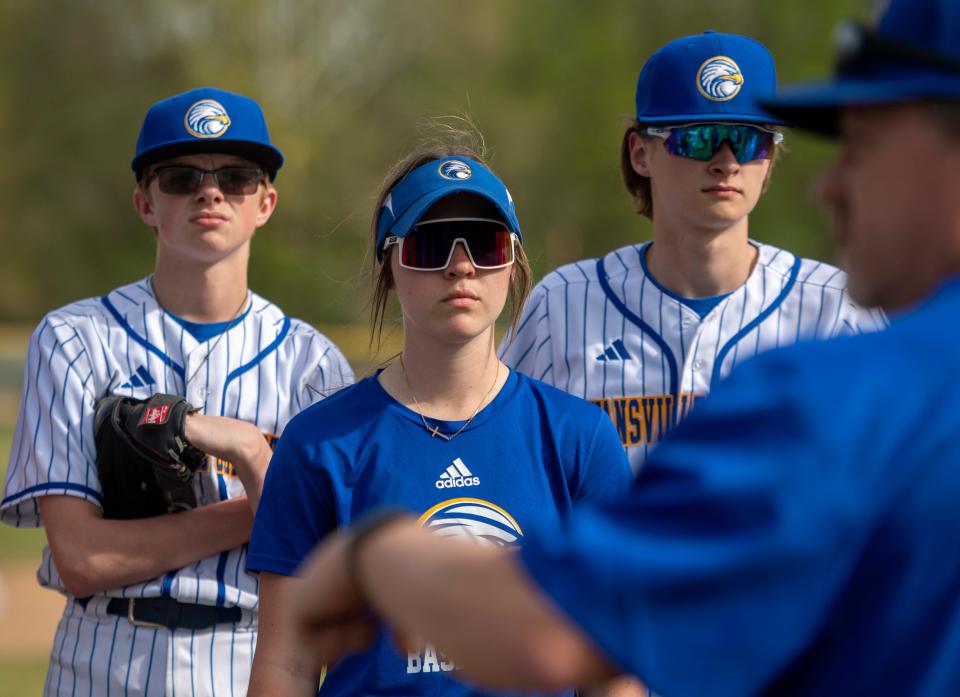 Evansville Christian’s Jacie Arnold, center, listens to coach Joe Paulin give direction during practice Wednesday, April 19, 2023.
