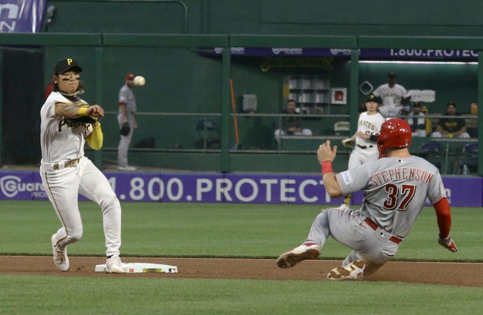Pirates second baseman Ji Hwan Bae (3) turns a double play over Reds catcher Tyler Stephenson (37) during the seventh inning at PNC Park.