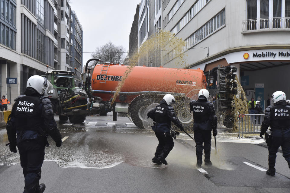 Farmers spray police with manure during a protest of farmers in the European Quarter outside a meeting of EU agriculture ministers in Brussels, Monday, Feb. 26, 2024. European Union agriculture ministers meet in Brussels Monday to discuss rapid and structural responses to the crisis situation facing the agricultural sector. (AP Photo/Harry Nakos)