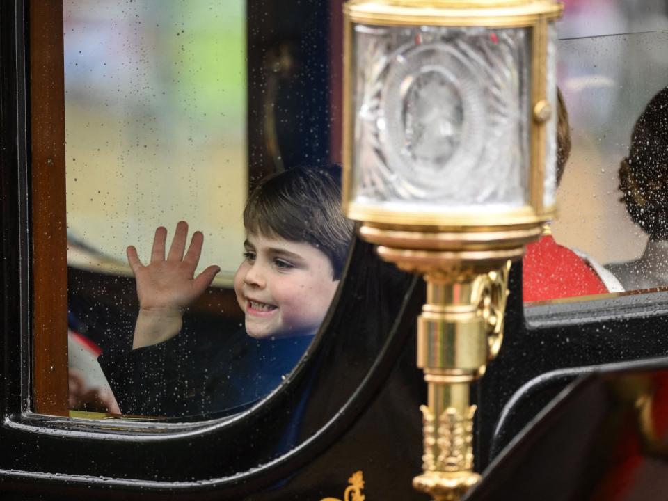 Prince Louis smiles through the window as he travels with his family back to Buckingham Palace from Westminster Abbey