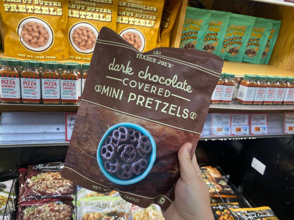 hand holding a bag of dark chocolate covered mini pretzels from trader joes