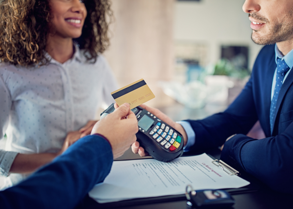 credit card transaction and man and woman renting a car in background