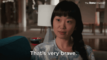 A woman sitting on her couch and saying, "that's very brave"