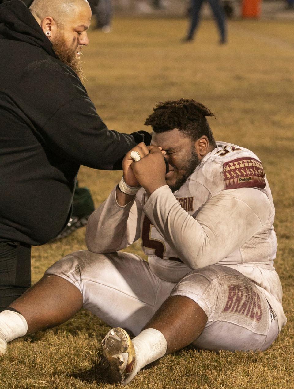 Lake Gibson defensive line coach Levi Hargrove consoles his player Jaremey McQueen (52) after their loss to Tampa Bay Tech during their Class 7A state semifinal playoff game in Tampa Friday night.