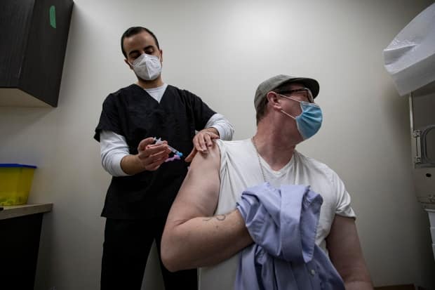 Pharmacist Kyro Maseh administers a dose of the AstraZeneca COVID-19 vaccine to Matthew Stone, 46, at a pharmacy in Toronto on Apr. 20, 2021. Ontario announced Tuesday the vaccine will no longer be offered to Ontarians as a first dose.