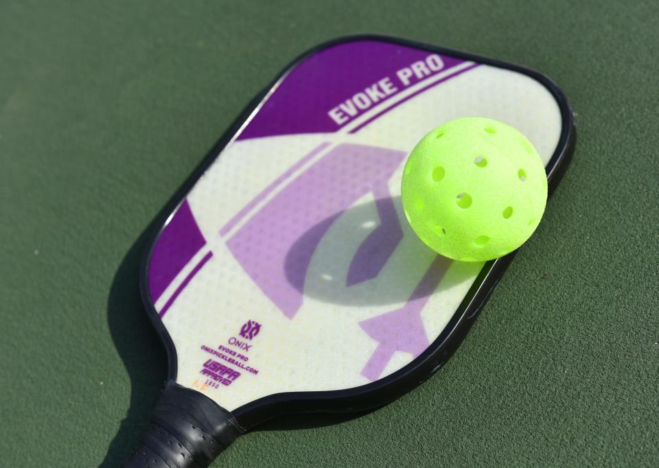 A pickleball paddle and ball 