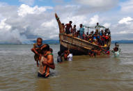 Smoke is seen on Myanmar's side of border as Rohingya refugees get off a boat after crossing the Bangladesh-Myanmar border through the Bay of Bengal in Shah Porir Dwip, Bangladesh September 11, 2017. REUTERS/Danish Siddiqui