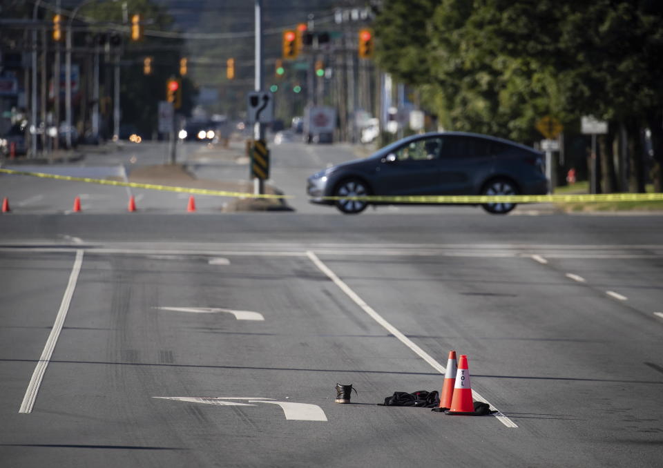 A shoe with blood on it and other belongings are seen on the road behind police tape at the scene of a shooting in Langley, British Columbia, Monday, July 25, 2022. Canadian police reported multiple shootings of homeless people Monday in a Vancouver suburb and said a suspect was in custody. (Darryl Dyck/The Canadian Press via AP)