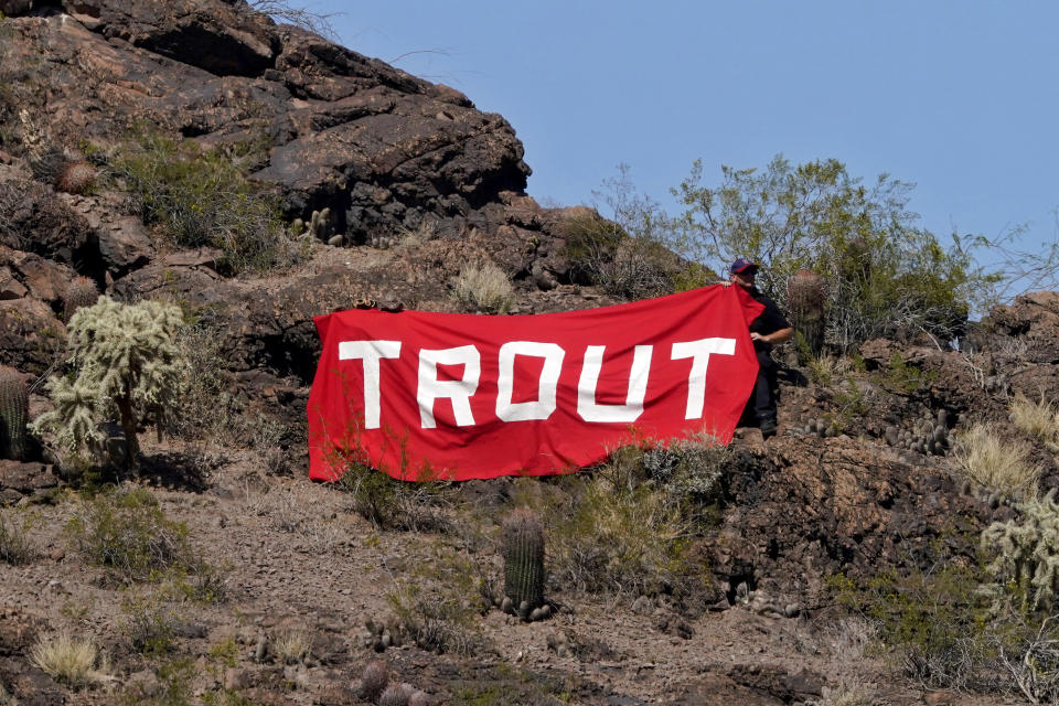 A fan holds a "Trout" sign on a hillside overlooking the ball park during the second inning of a spring training baseball game between the Los Angeles Angels and the Chicago Cubs, Monday, March 22, 2021, in Tempe, Ariz. (AP Photo/Matt York)