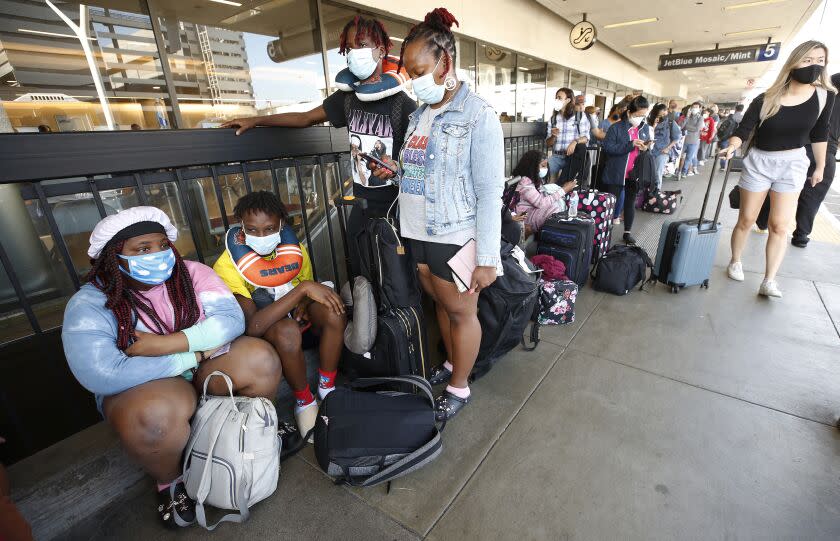 LOS ANGELES, CA - AUGUST 03: Kyrianna, Te'Shawn, and Brandon Hill, with their Mother Katyra Henderson-Hill, left to right, are trying travel back home to Chicago waiting with other passengers as they form a line that extends outside LAX Terminal 5 Tuesday morning as Spirit Airlines has canceled 313 flights on Monday, 40% of its scheduled flights, and 210 flights have been delayed. Stemming from a problem that began over the weekend, hundreds of Spirit Airlines flights were canceled nationwide leading to issues with dozens of arrivals and departures at LAX Los Angeles International Airport. LAX Airport on Tuesday, Aug. 3, 2021 in Los Angeles, CA. (Al Seib / Los Angeles Times).