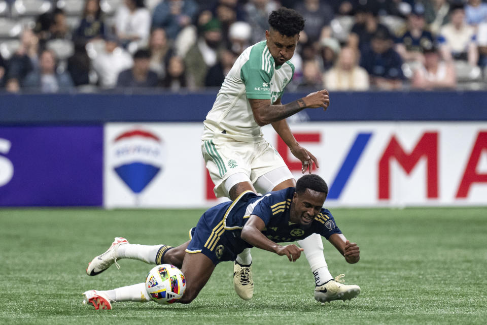 Vancouver Whitecaps' Ali Ahmed, bottom, falls in front of Austin FC's Julio Cascante (18) as they vie for the ball during the first half of an MLS soccer match in Vancouver, British Columbia, on Saturday, May 4, 2024. (Ethan Cairns/The Canadian Press via AP)