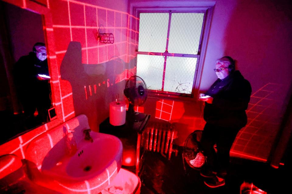 In the haunted dressing room upstairs at the Redford Theatre, Sarah Rupert, 58, of Rockwood, a member of the Motor City Ghost Hunters,  communicates with a spirit. Rupert uses a device called a G3 which projects a red grid on the wall to see whether a spirit walks through the grid during the teams "adult walk" at the theatre in Redford on Friday, Oct. 7, 2022,