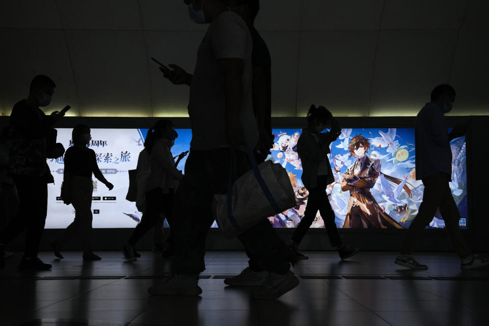 Commuters walk by a computer and mobile phone's RPG games advertisement at a subway station in Beijing Tuesday, Sept. 14, 2021. China has set new rules limiting the amount of time kids can spend playing online games. (AP Photo/Andy Wong)