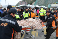 A rescued passenger from a ferry sinking off South Korea's southern coast, is carried by rescue teams on his arrival at Jindo port in Jindo, south of Seoul, South Korea, Wednesday, April 16, 2014. Dozens of military boats and helicopters scrambled Wednesday to rescue more than 470 people, including 325 high school students on a school trip, after the ferry sank off South Korea's southern coast, officials said. (AP Photo/Park Chul-heung, Yonhap) KOREA OUT