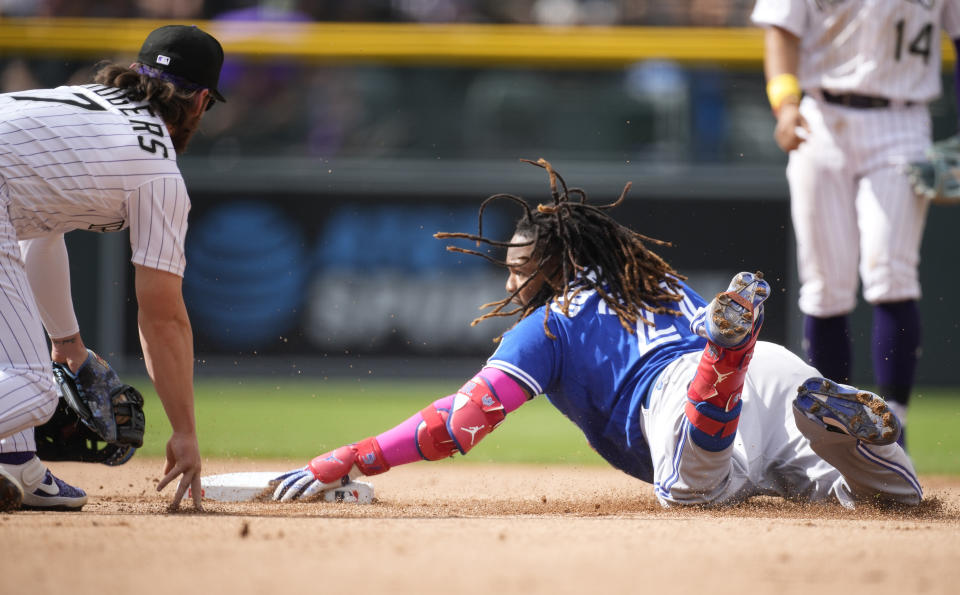 Toronto Blue Jays' Vladimir Guerrero Jr., front right, slides safely into second base with an RBI double as Colorado Rockies second baseman Brendan Rodgers, left, turns to apply a late tag in the fifth inning of a baseball game Sunday, Sept. 3, 2023, in Denver. (AP Photo/David Zalubowski)