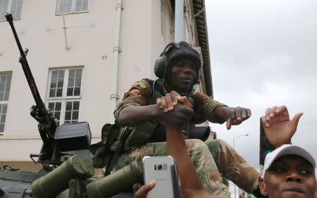 Protesters calling for Zimbabwean President Robert Mugabe to step down greet a soldier in Harare, Zimbabwe, November 18, 2017. REUTERS/Philimon Bulawayo