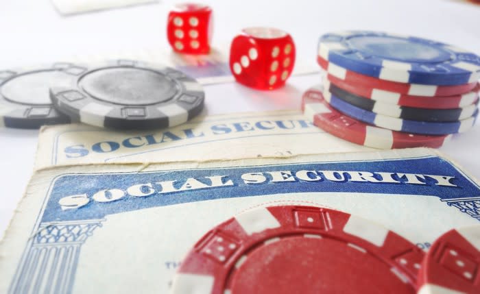 Red dice and casino chips laid atop two Social Security cards.